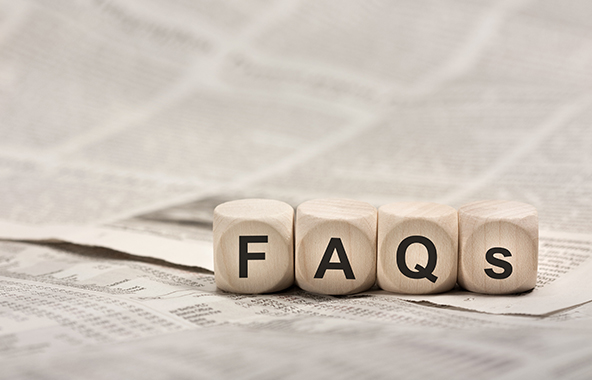 Wooden blocks spelling FAQs on top of a newspaper.