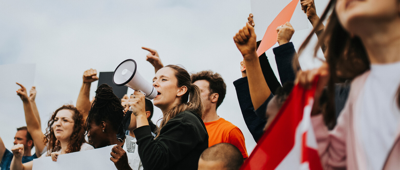 People holding signs and using a megaphone at a public demonstration.