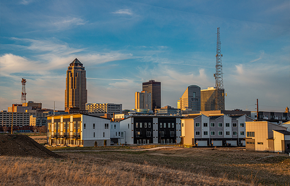 Des Moines skyline at sunset with buildings and communication towers.