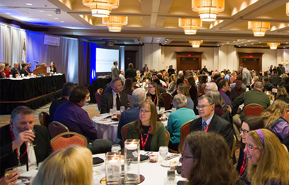 Newspaper professionals attending a convention in a hotel ballroom.