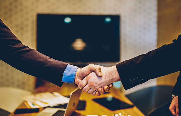 Two professionals shaking hands during a business meeting.