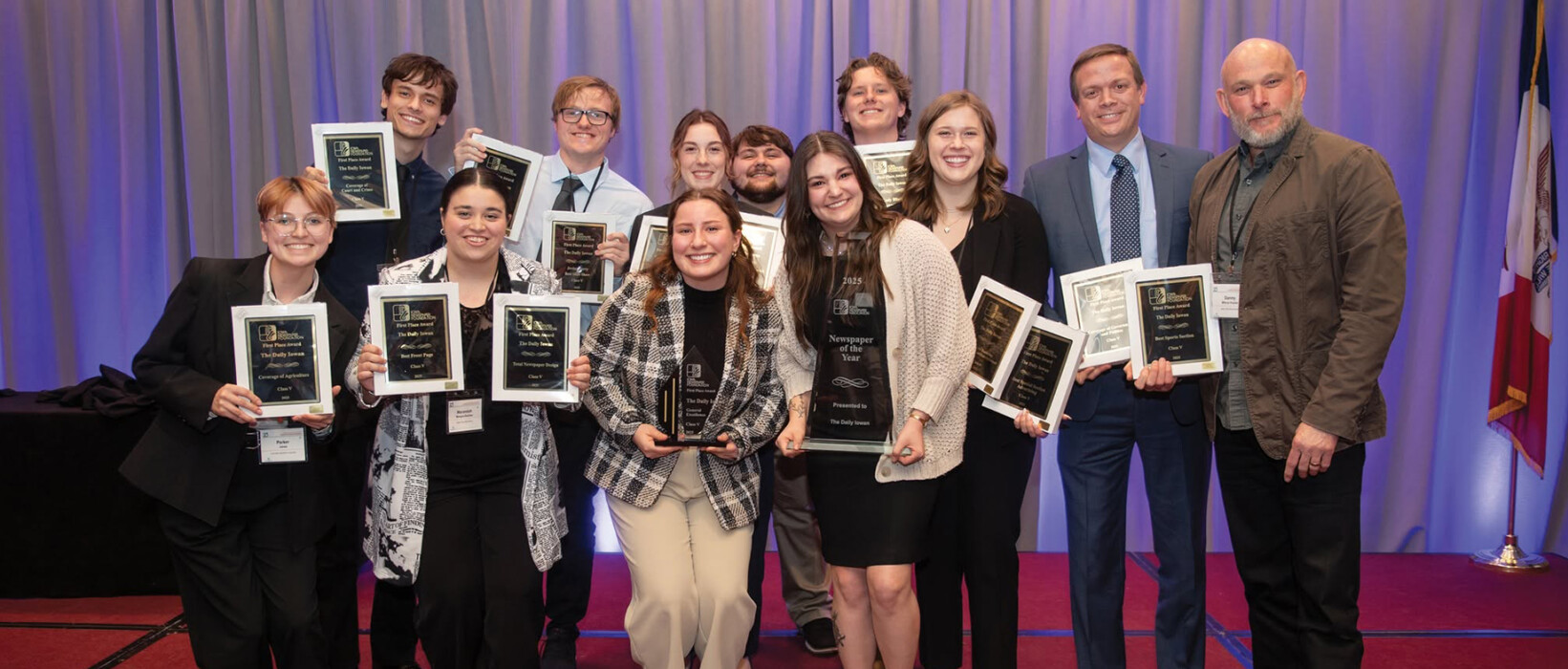 Group of newspaper professionals holding awards at an Iowa Newspaper Association event.