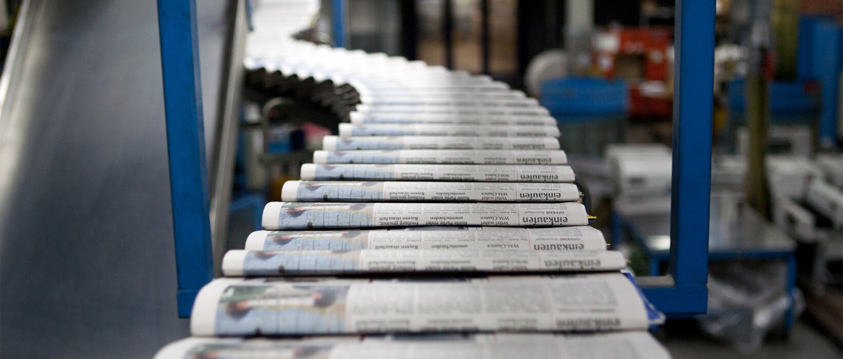 Newspapers lined up on a production conveyor.